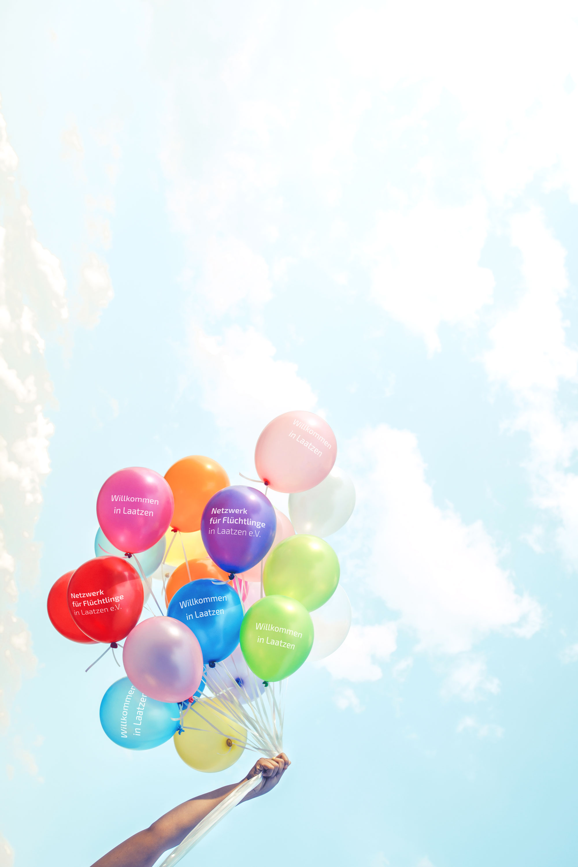 Farbige Luftballons fliegen in die Luft. Auf den Luftballons steht 'Netzwerk für Flüchtlinge in Laatzen e.V.'